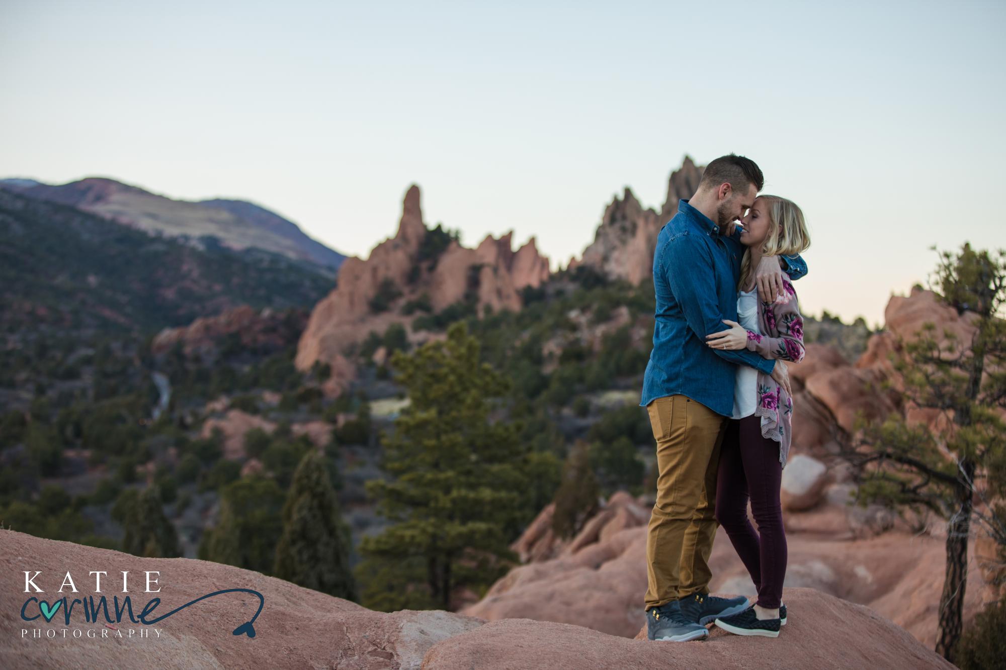 Newly engaged Colorado springs couple kiss on top of mountain