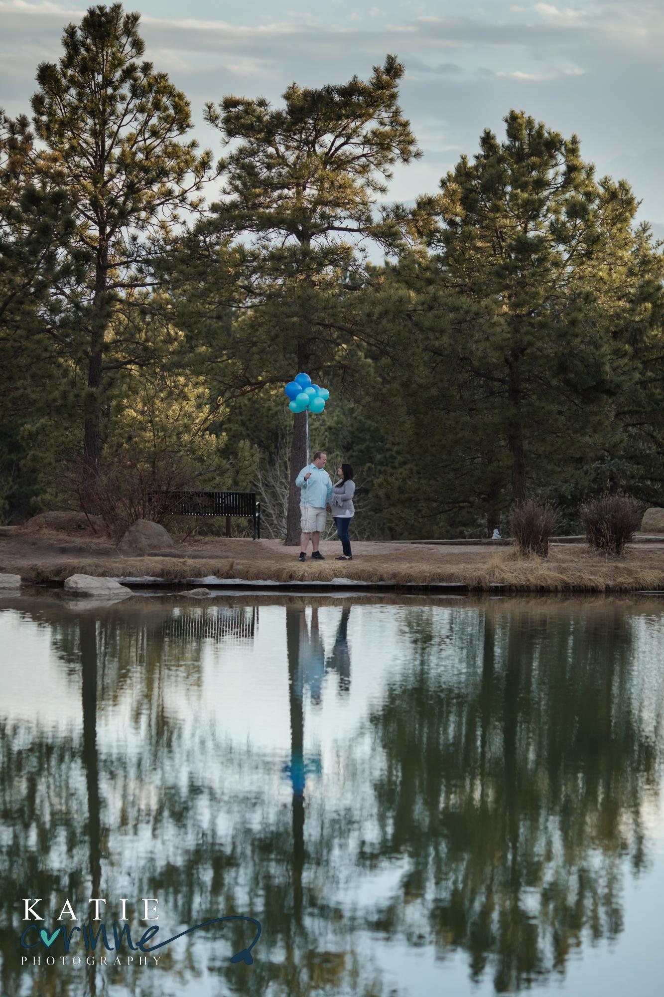 Pregnant couple hold blue balloons to announce gender of baby
