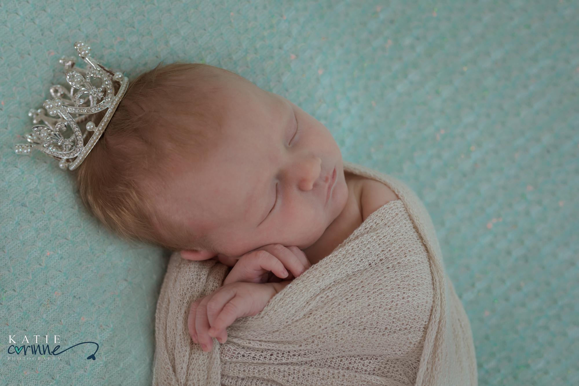 newborn posed and wearing tiny crown