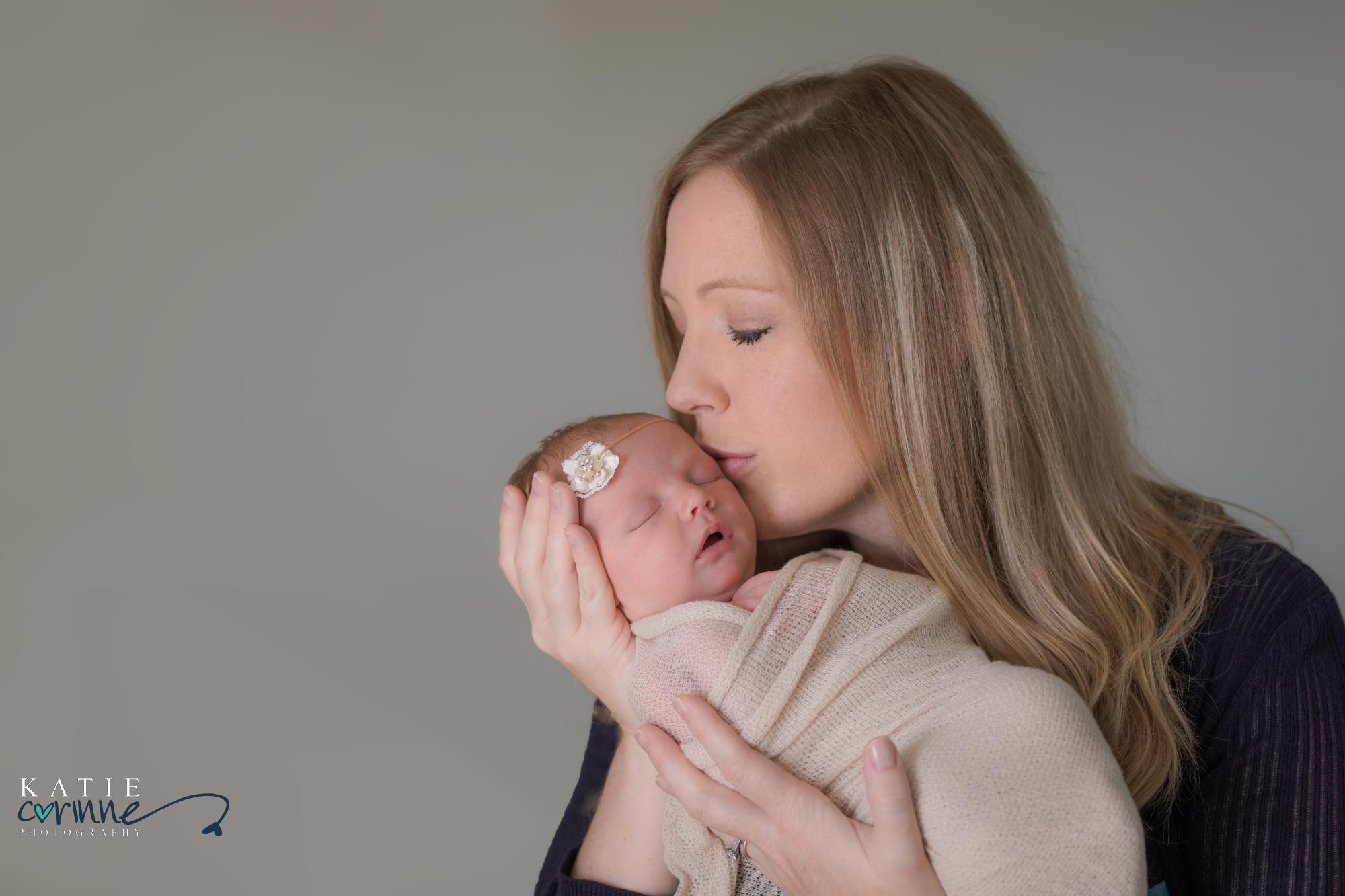 Mother kisses newborn daughter in photo studio