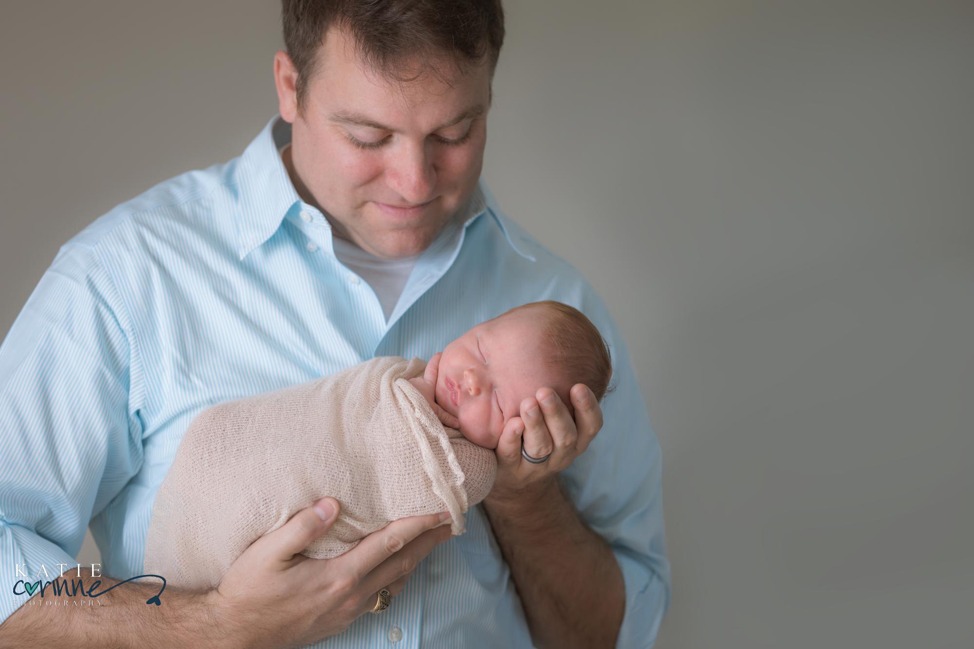 Father looks at newborn baby in mobile photo studio