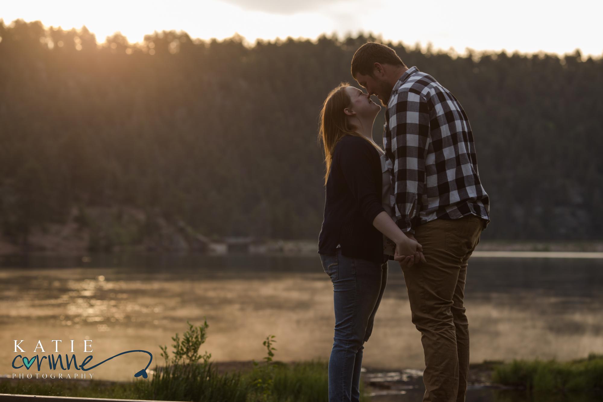 engaged couple kiss in front of mountains