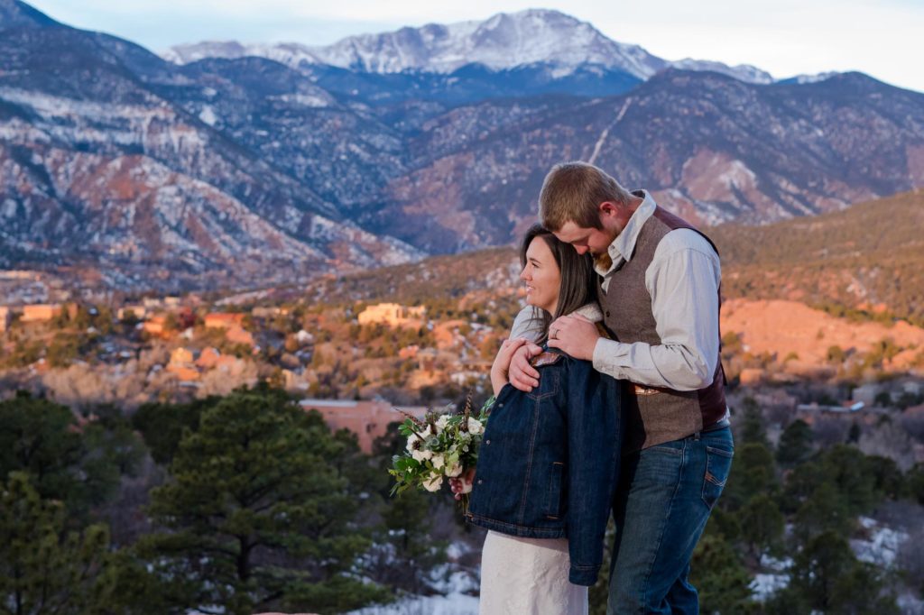 engaged couple snuggling in front of pikes peak