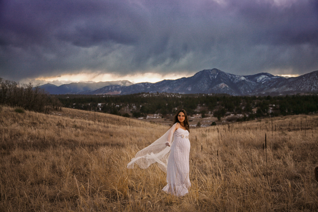 a pregnant woman in a field with the mountains, second maternity session