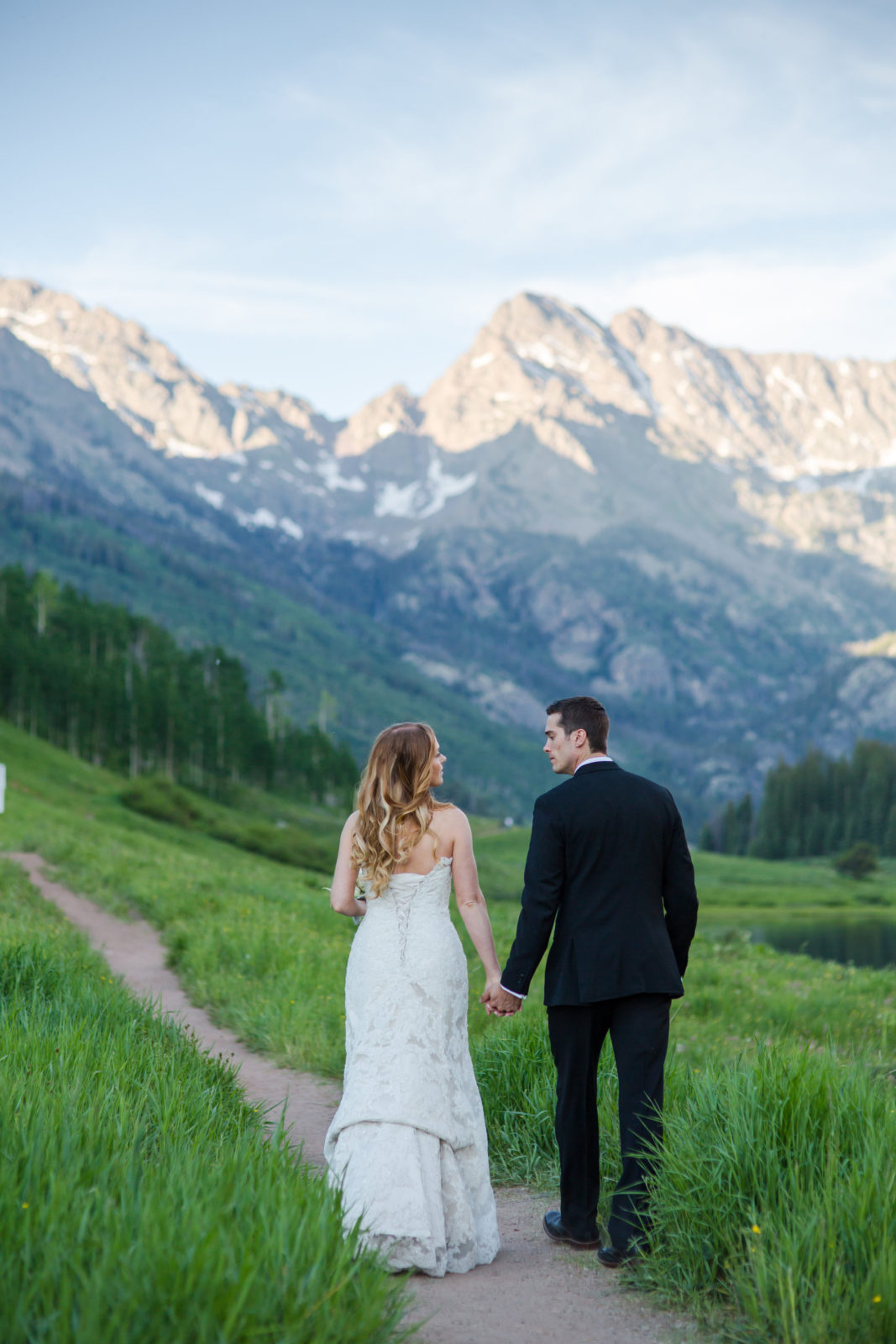 bride and groom walking towards mountains