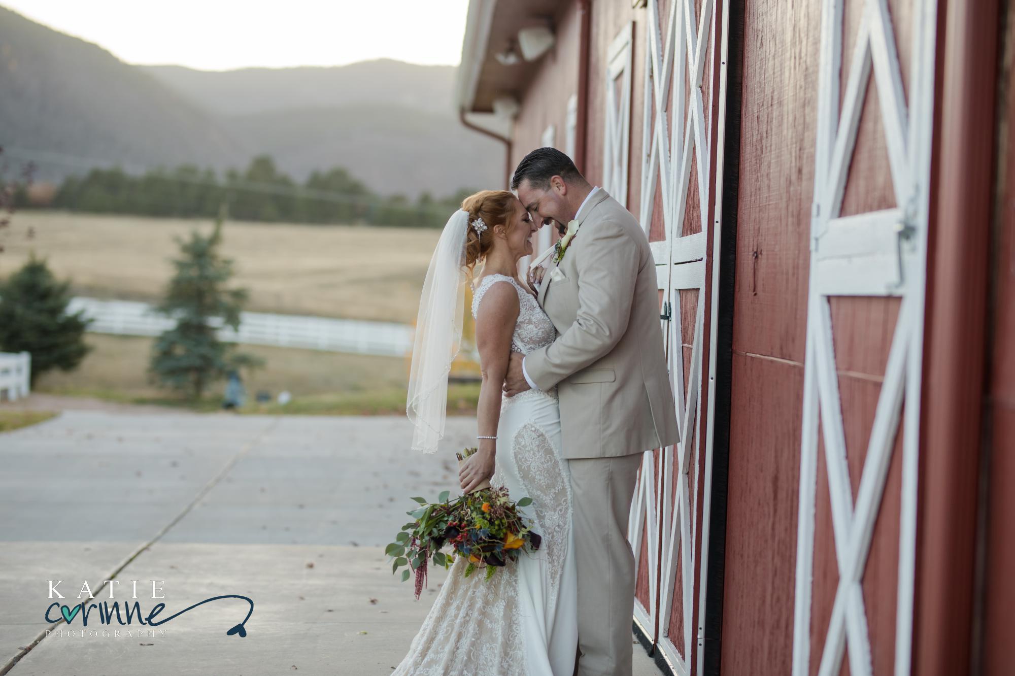 bride and groom kiss in front of red barn