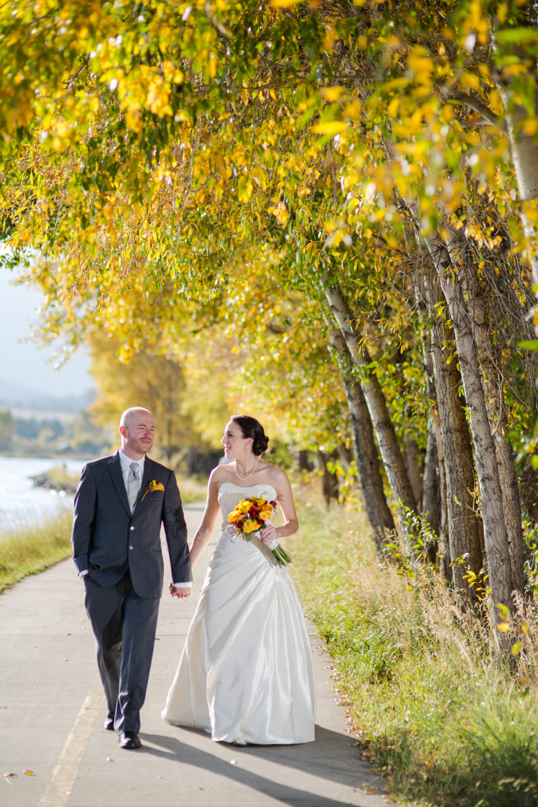 bride and groom walking in fall foliage in estes park