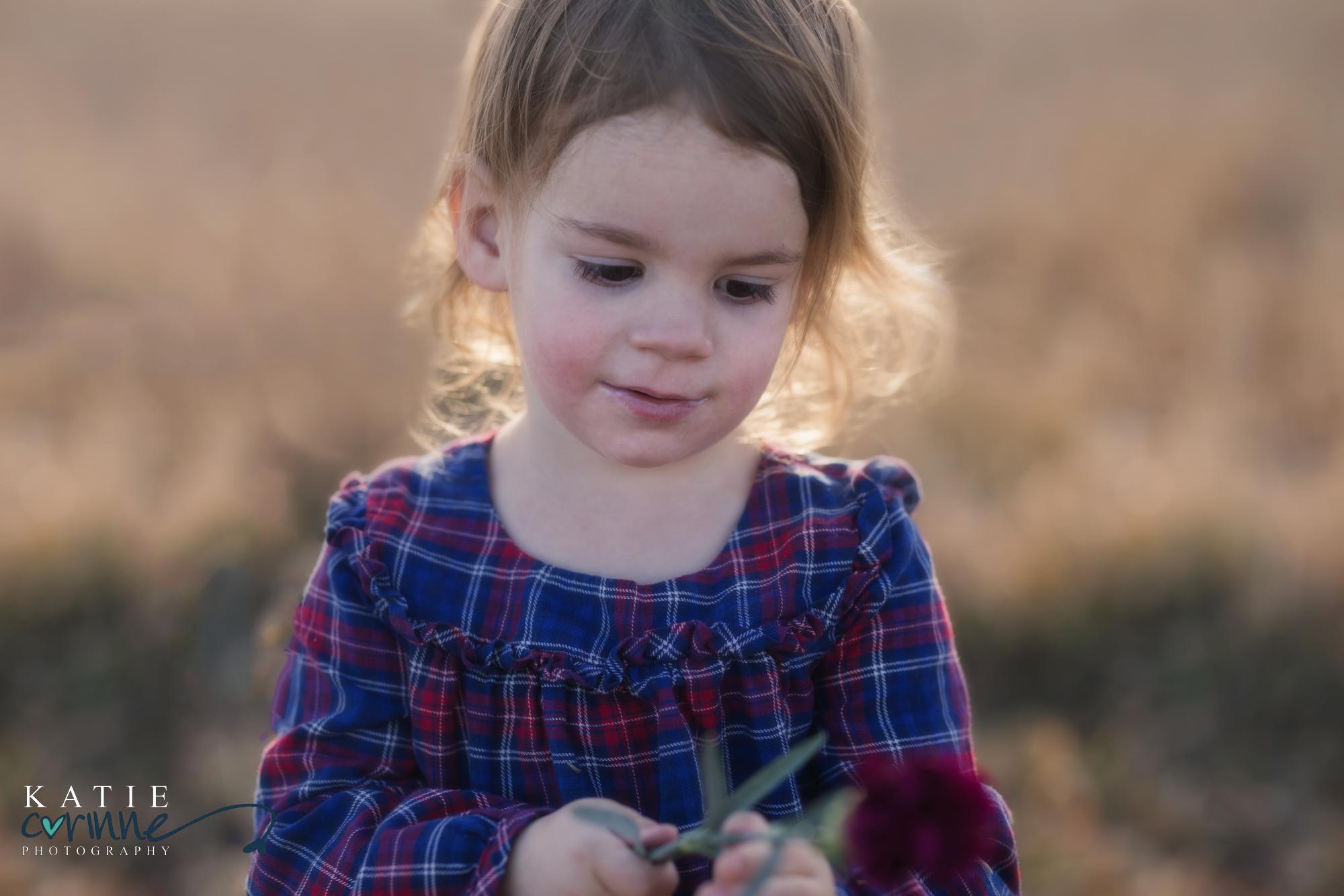 5 year old girl looks at flower and smiles