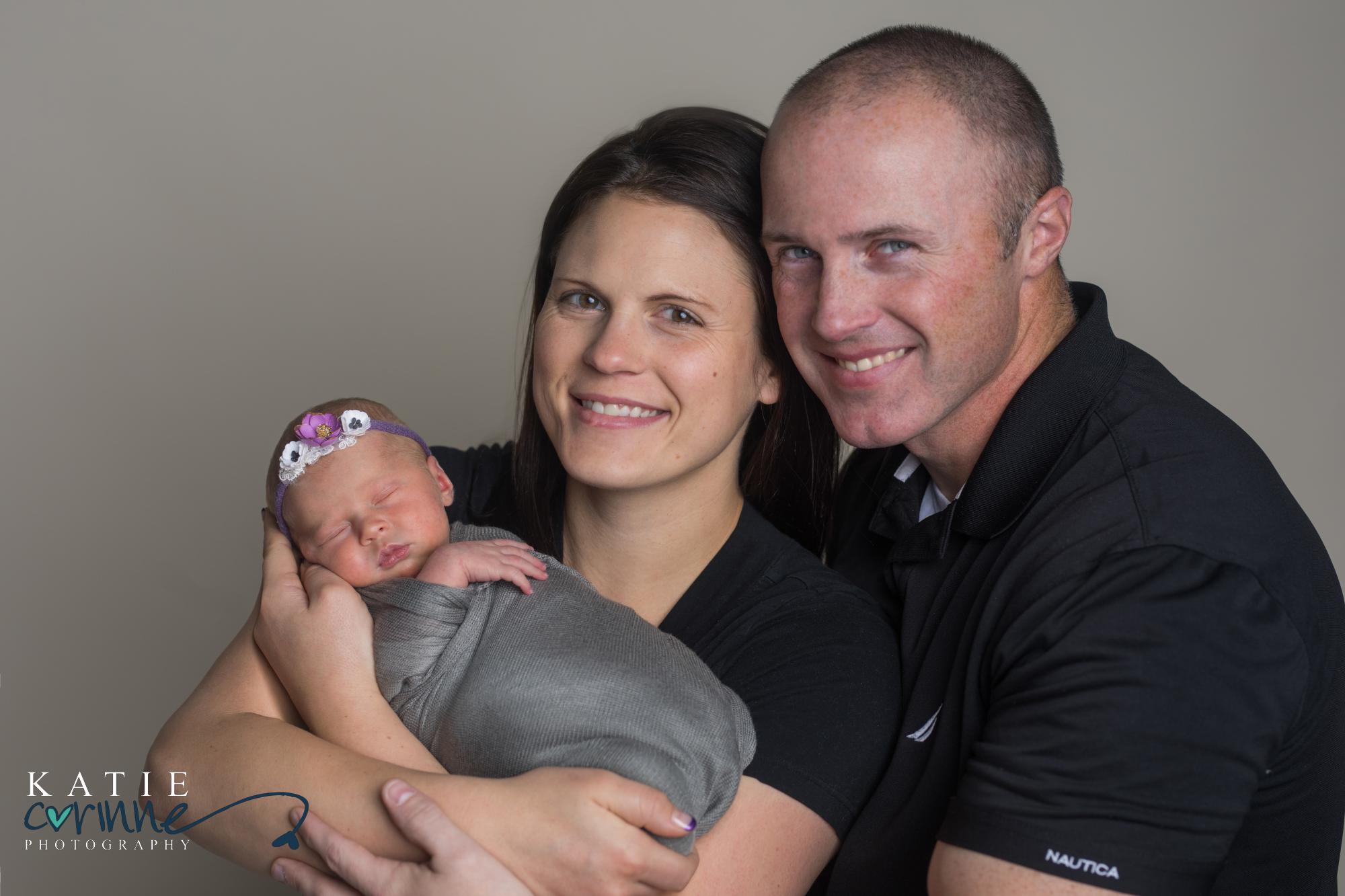 parents hold newborn daughter and smile at camera in Monument Colorado photography studio