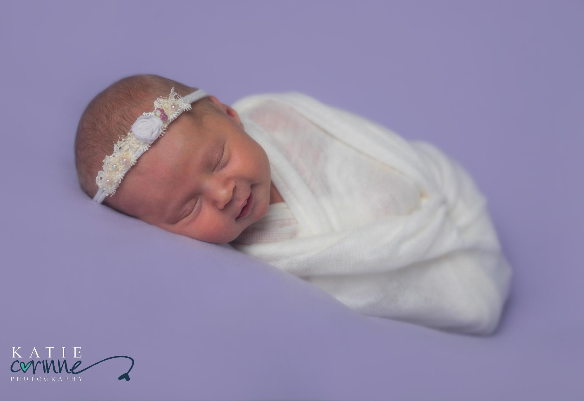 newborn baby girl on purple blanket