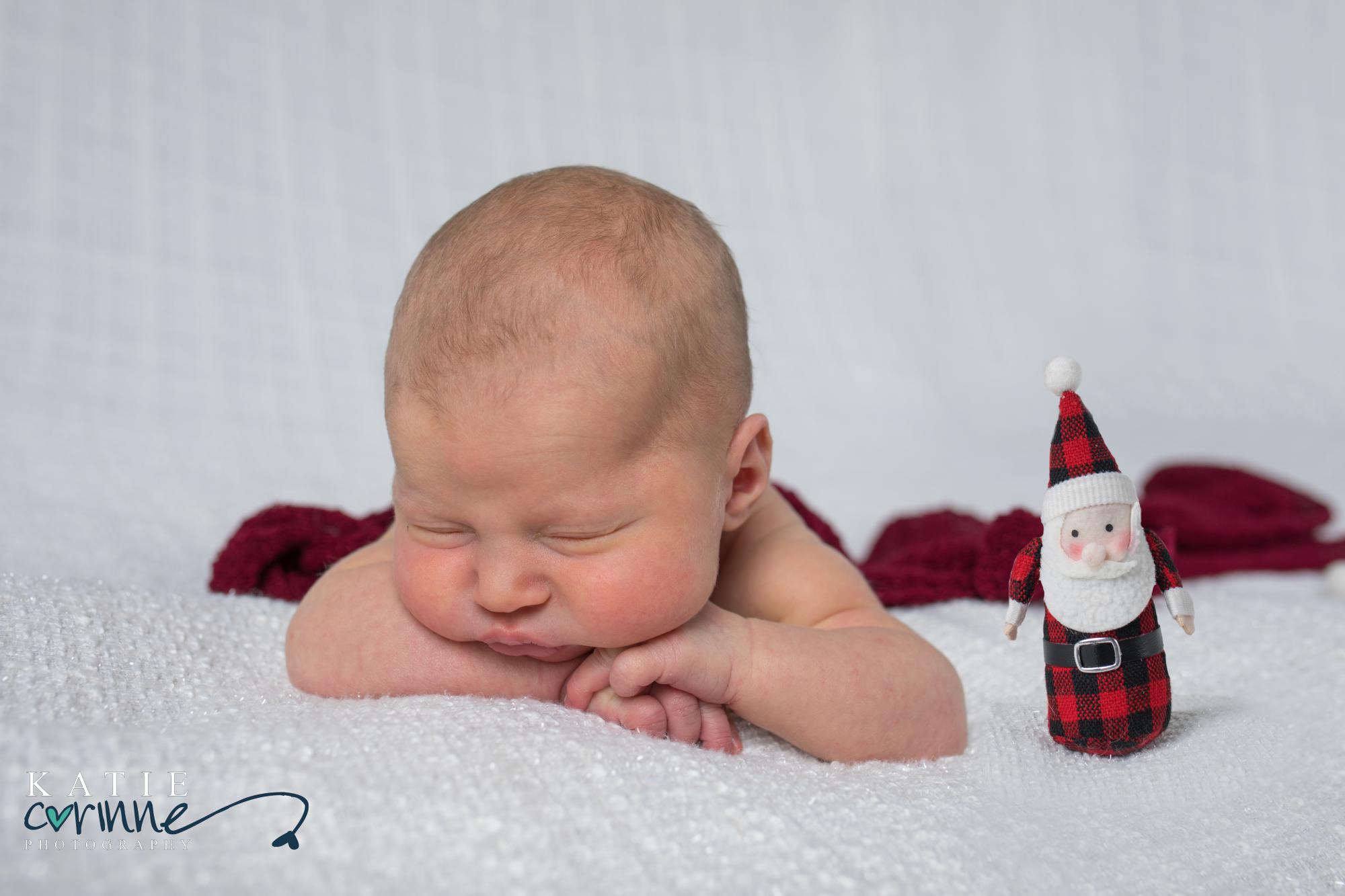 Colorado newborn girl posed with christas colors and santa doll