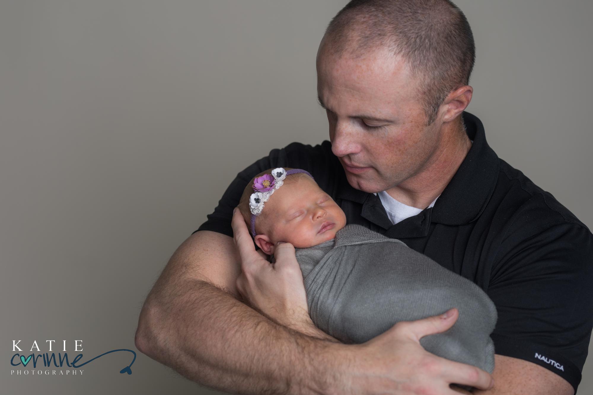 father holds swaddled newborn baby girl