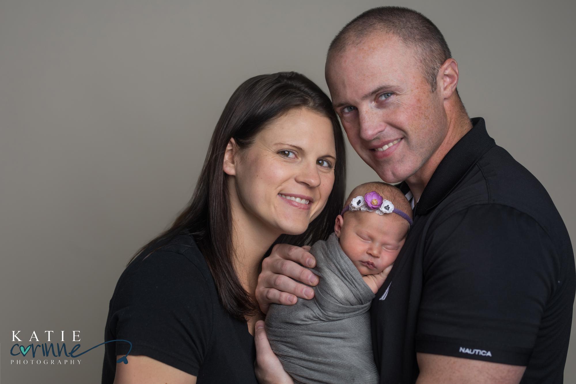 girl newborn being held by smiling parents