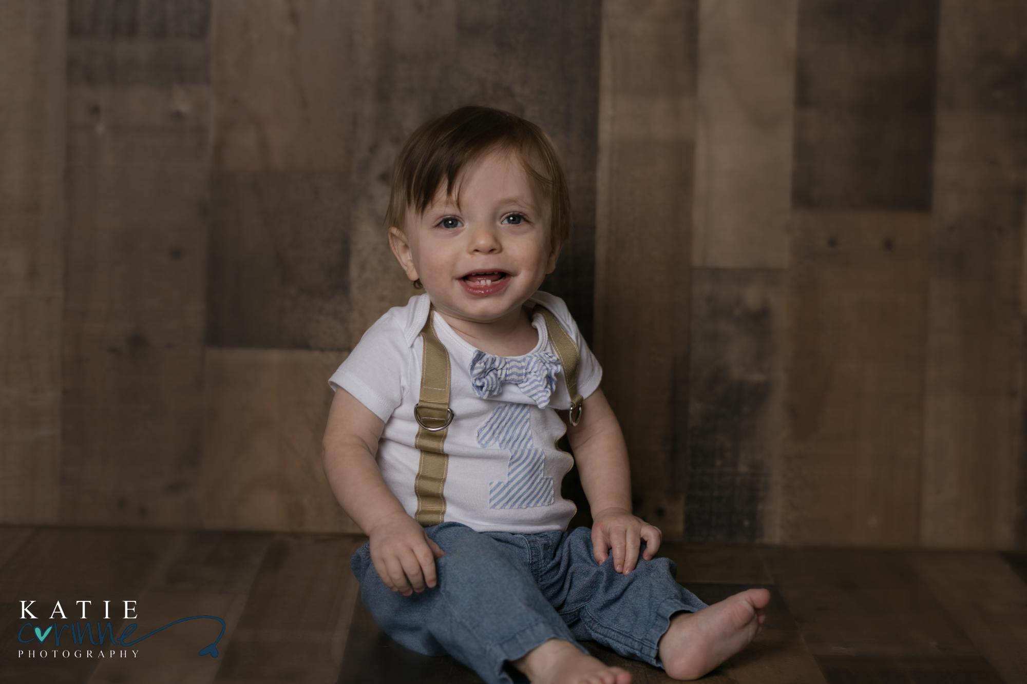Colorado baby sits in front of wood backdrop