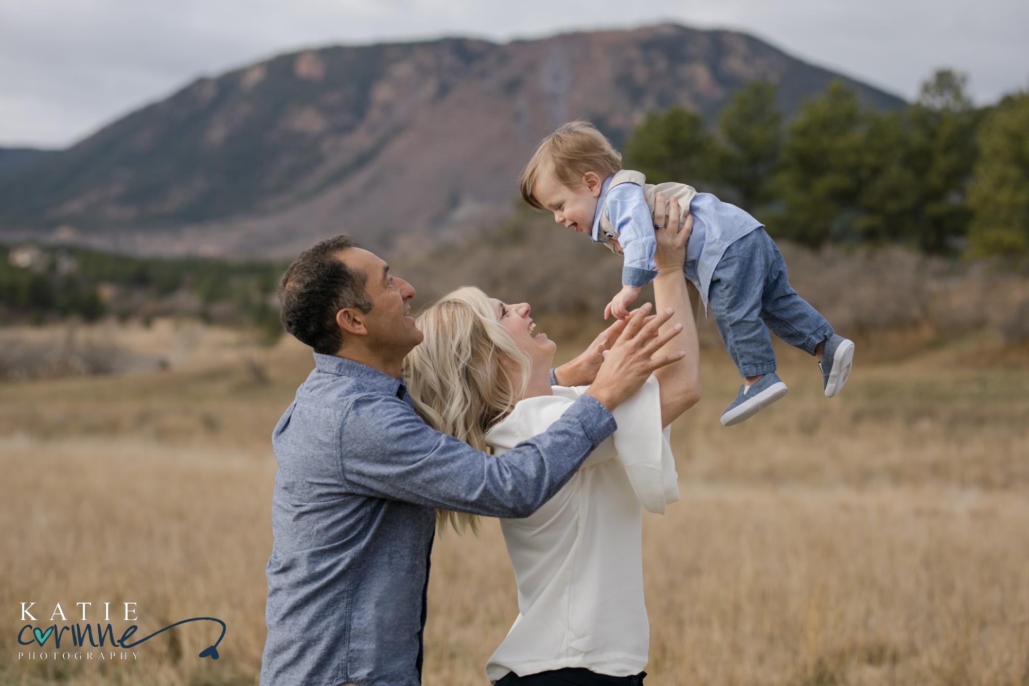 Palmer Lake parents play with one year old in front of Colorado landscape