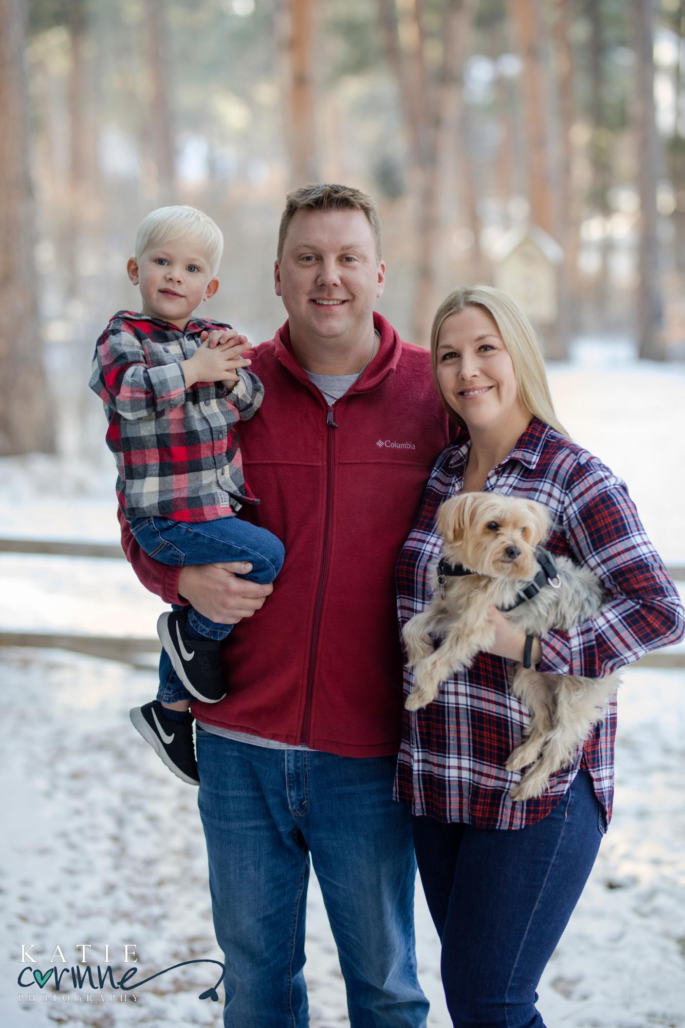 Family of three poses for Christmas Photos with their small dog