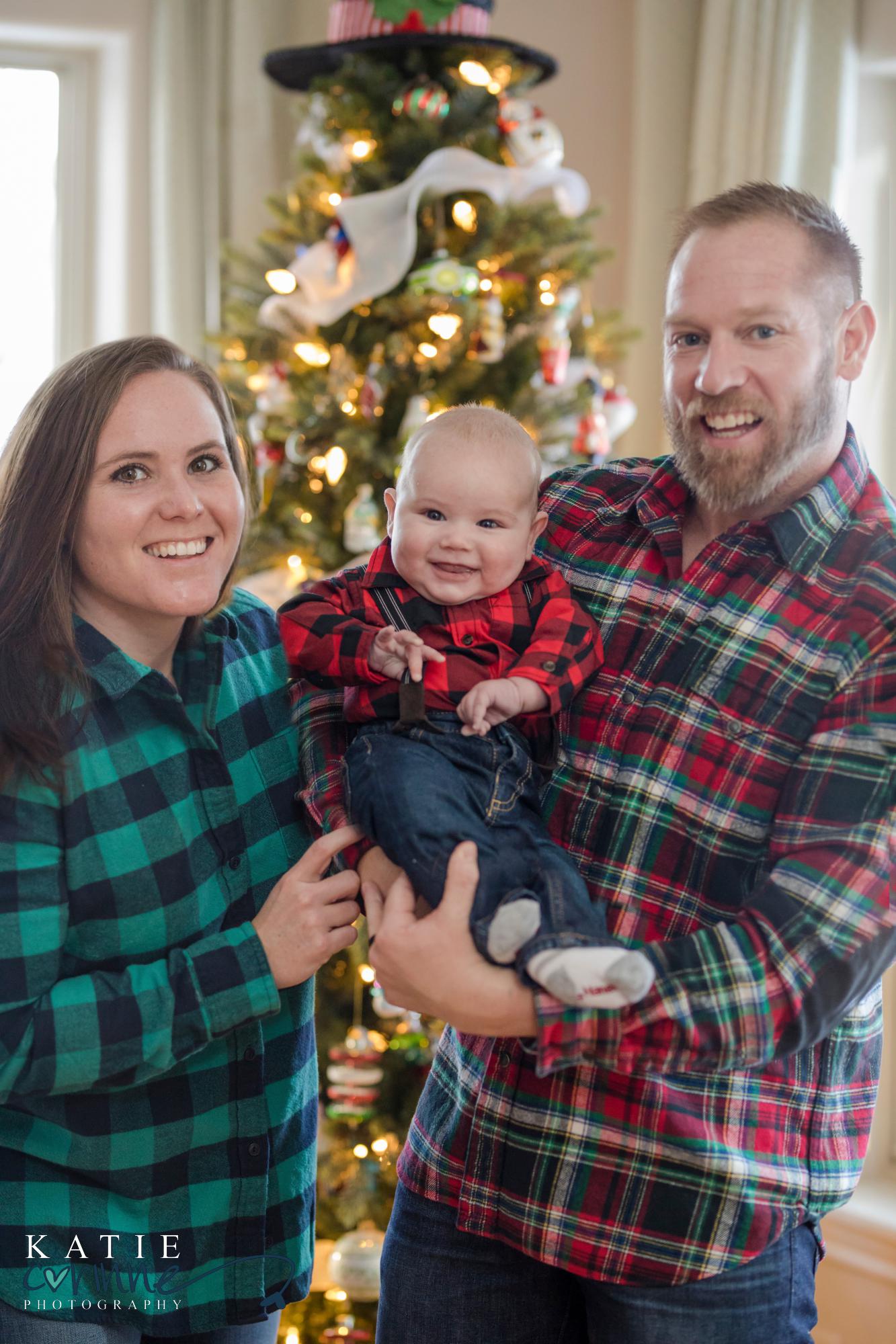 plaid clad couple pose for Photographer with their baby