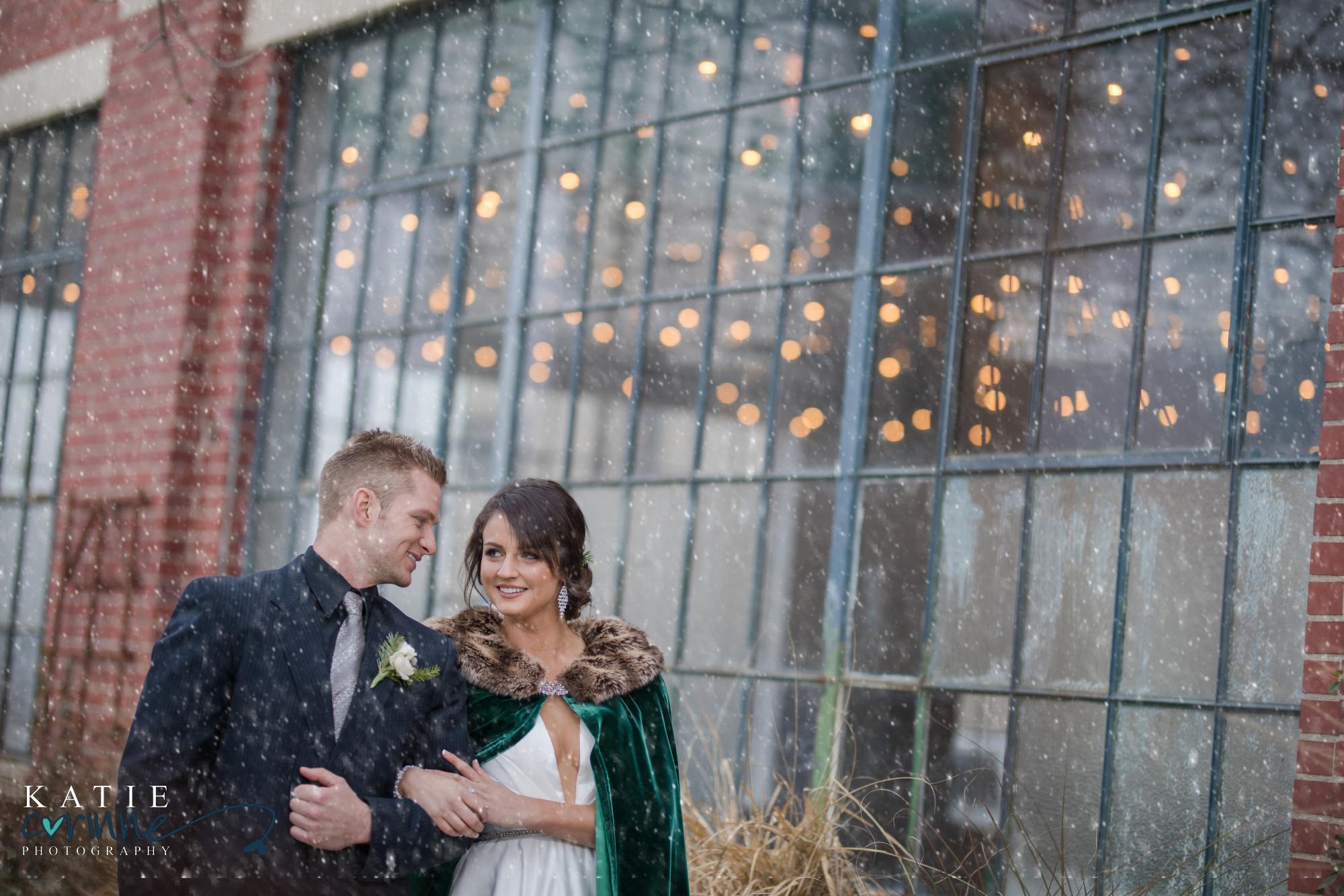 bride and groom hook arms in front of Moss Denver on snowy day