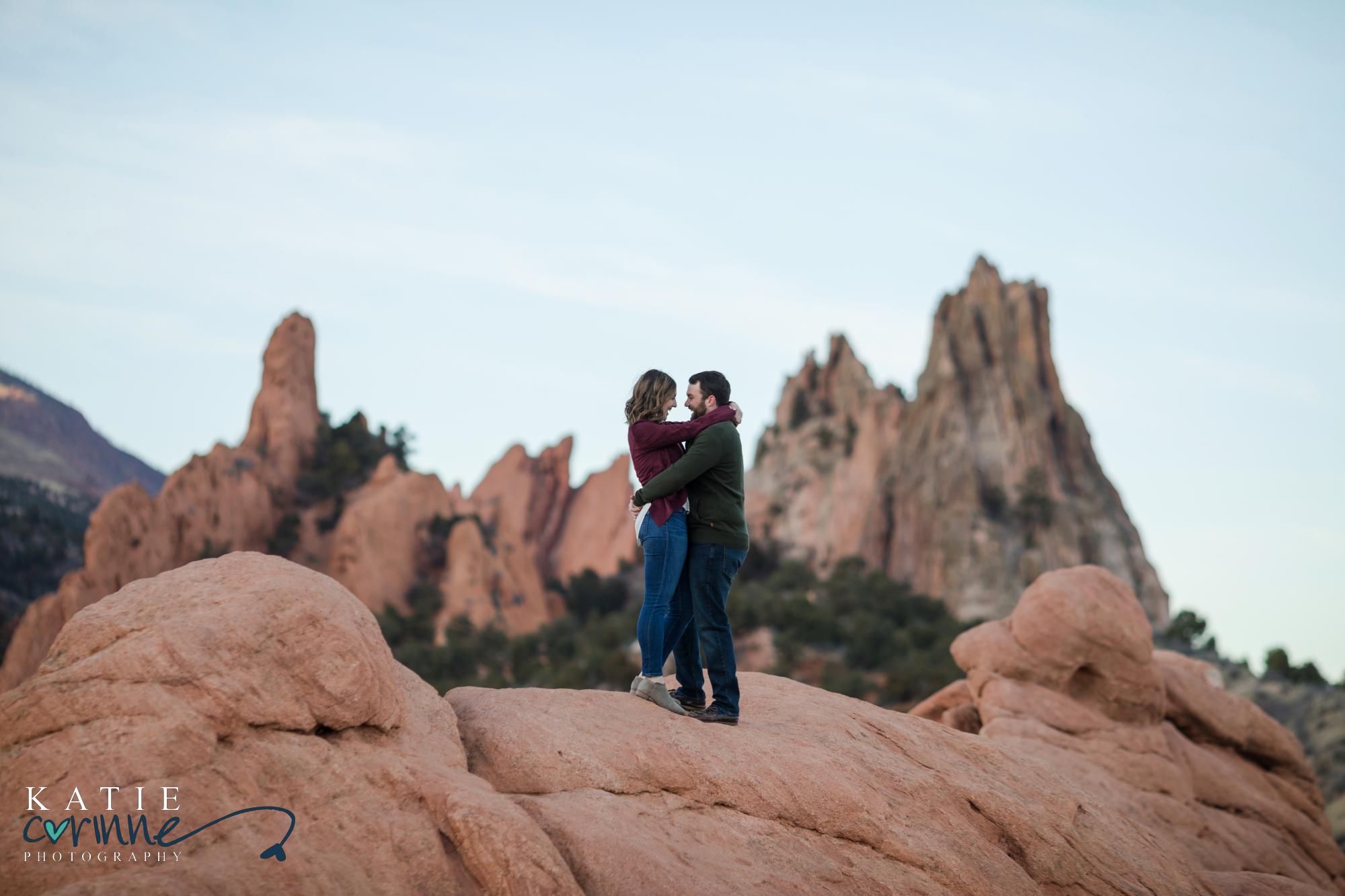 engaged couple hold each other amid jagged mountainscape