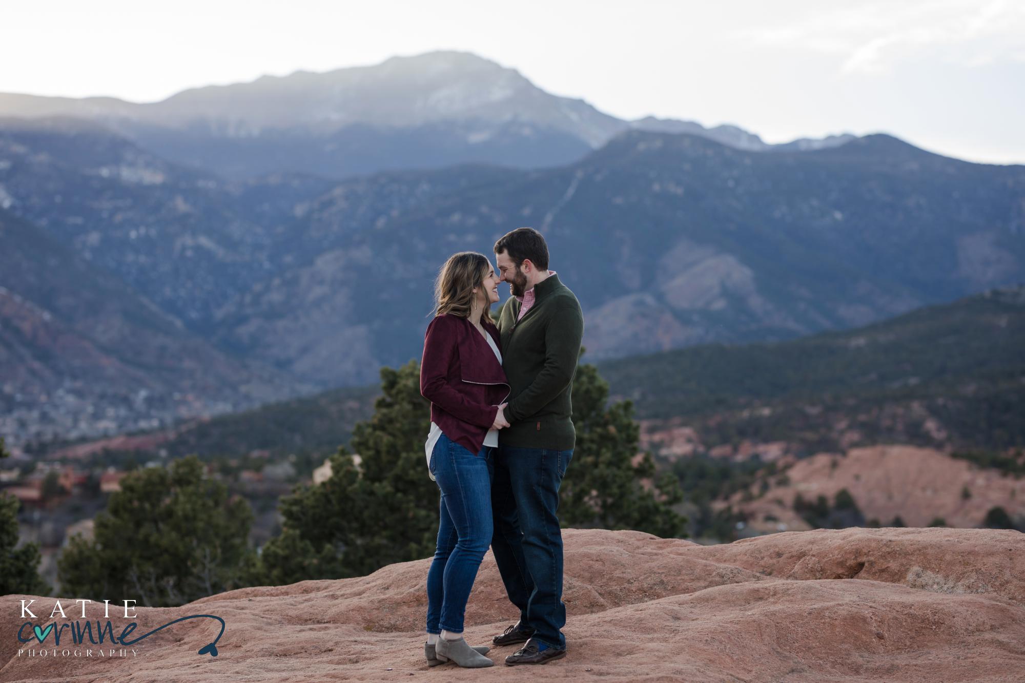 couple stands on red rocks at engagement session