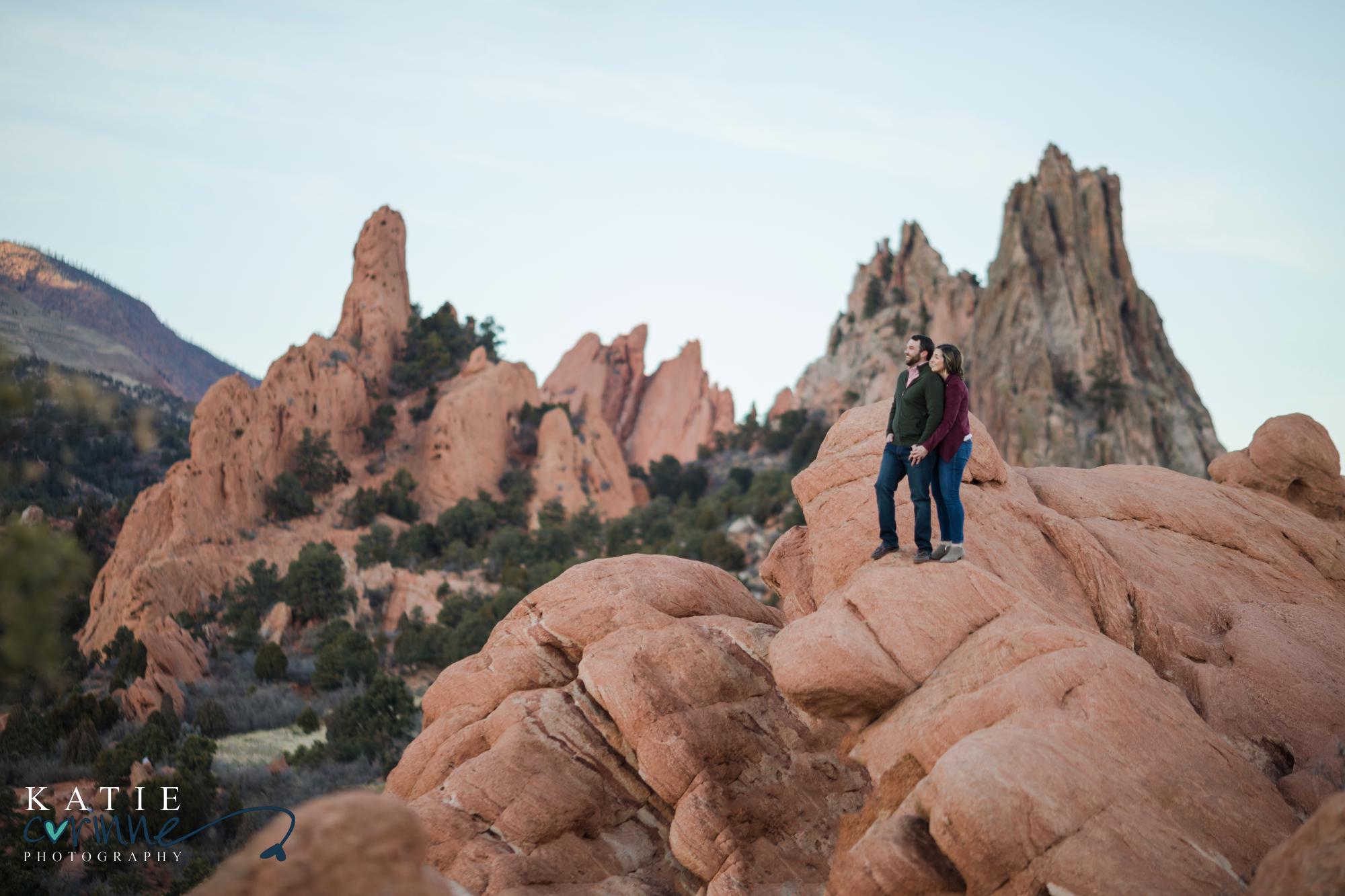 couple gaze out into distance together surrounded by red rocks