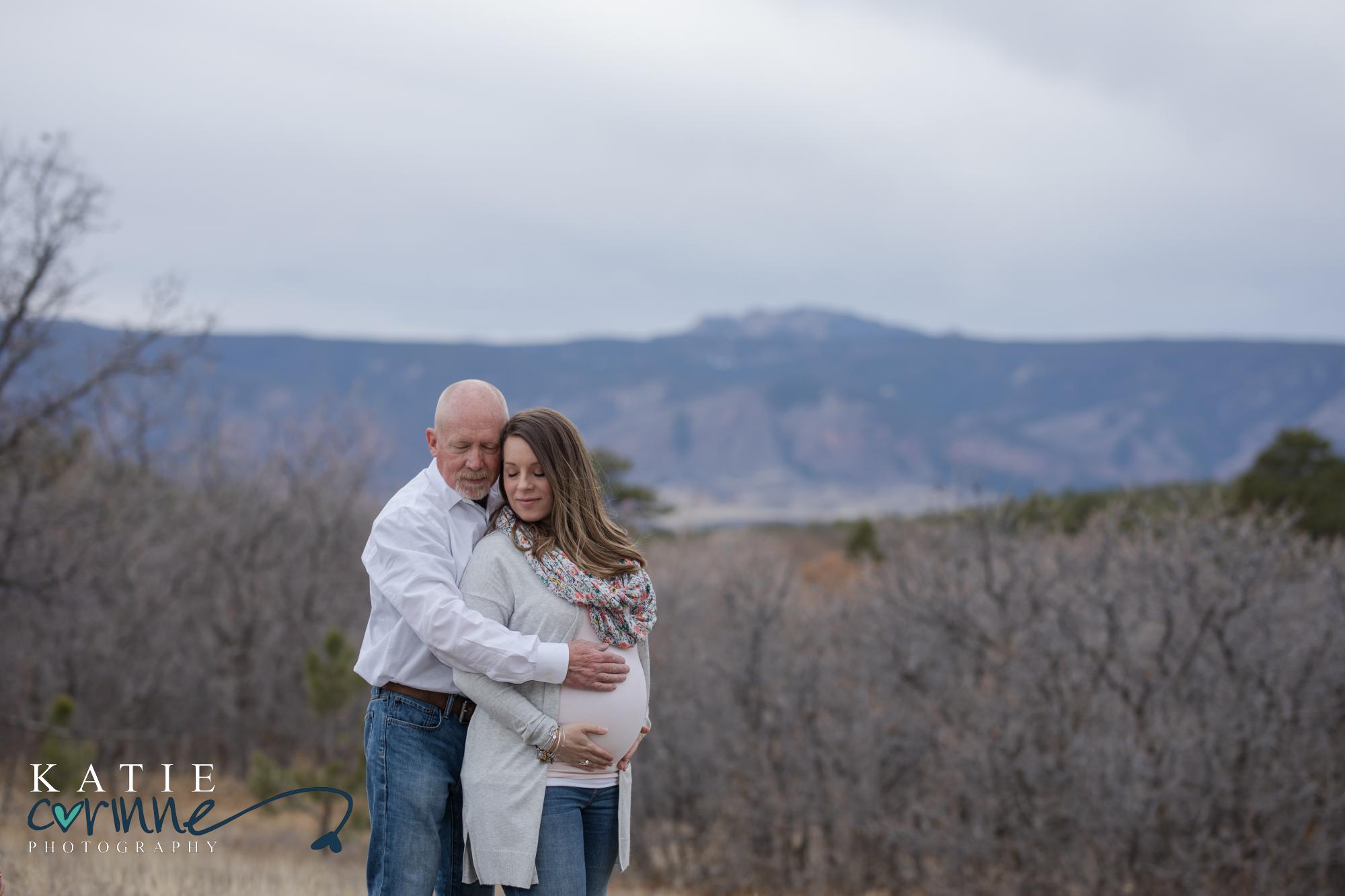 pregnant couple in front of Colorado mountain range