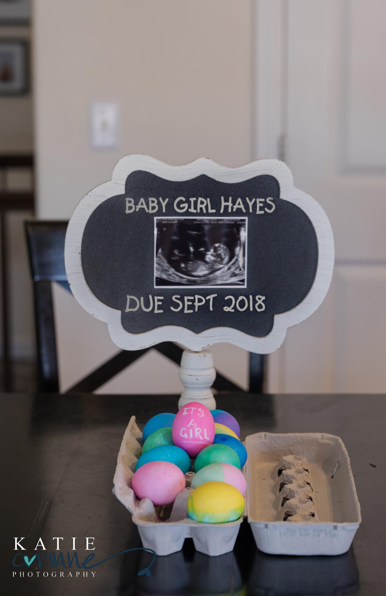 sign shows due date of baby girl above colorful Easter eggs