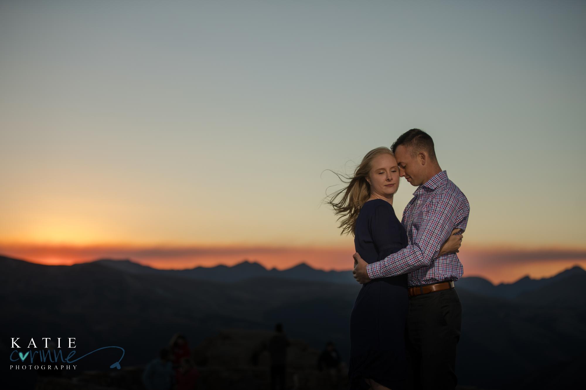 Colorado engaged couple pose in front of sunset mountains
