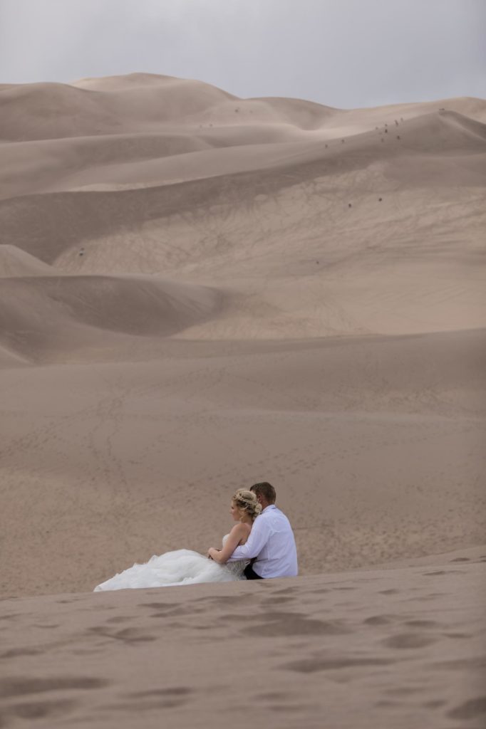 Bride and groom hold each other at sand dunes