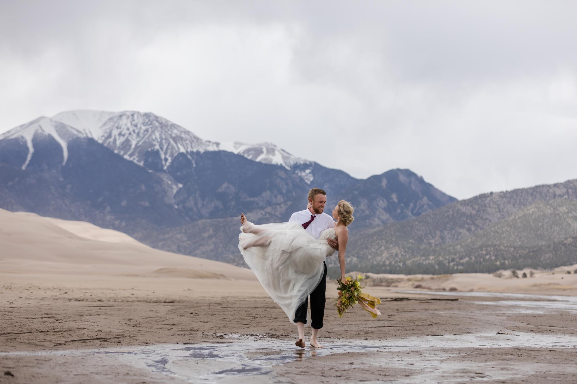 Groom picks up bride on sand dunes