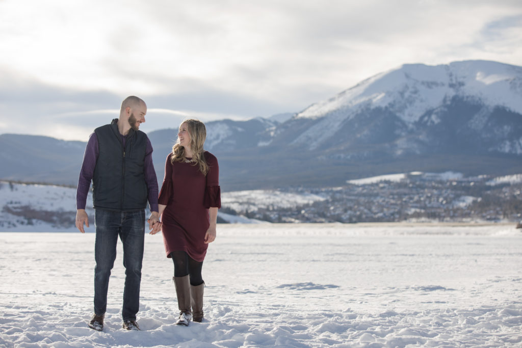 Engaged couple walking on frozen Colorado lake