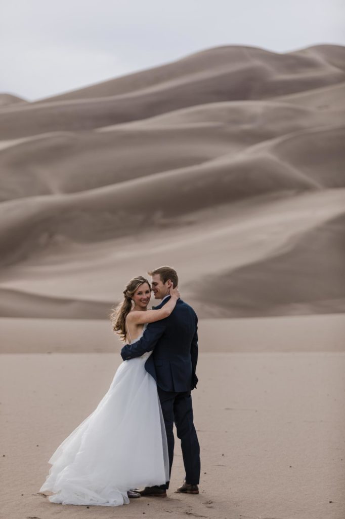 denver wedding couple kiss on sand dunes