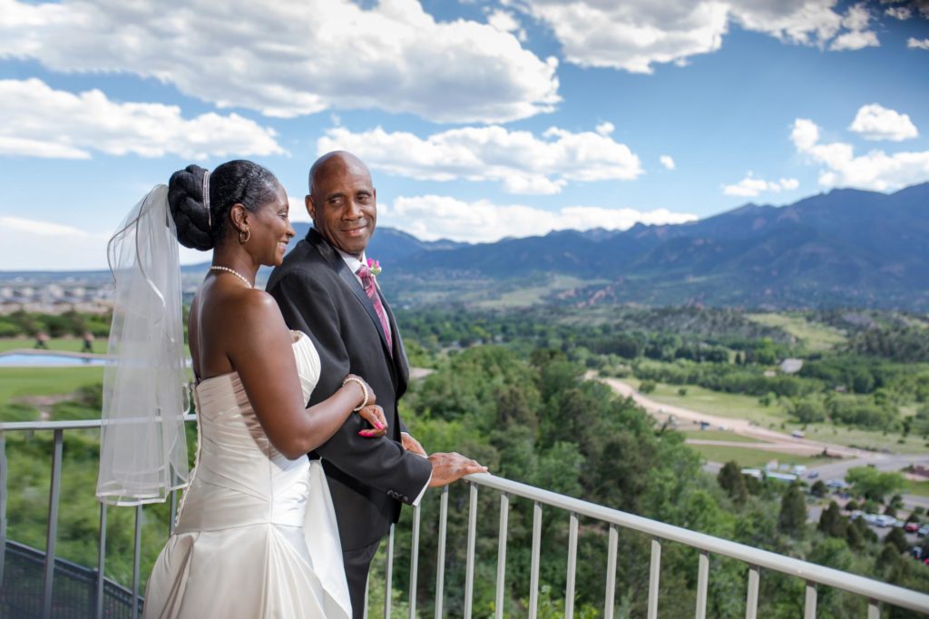 couple overlooks rocky mountains from balcony