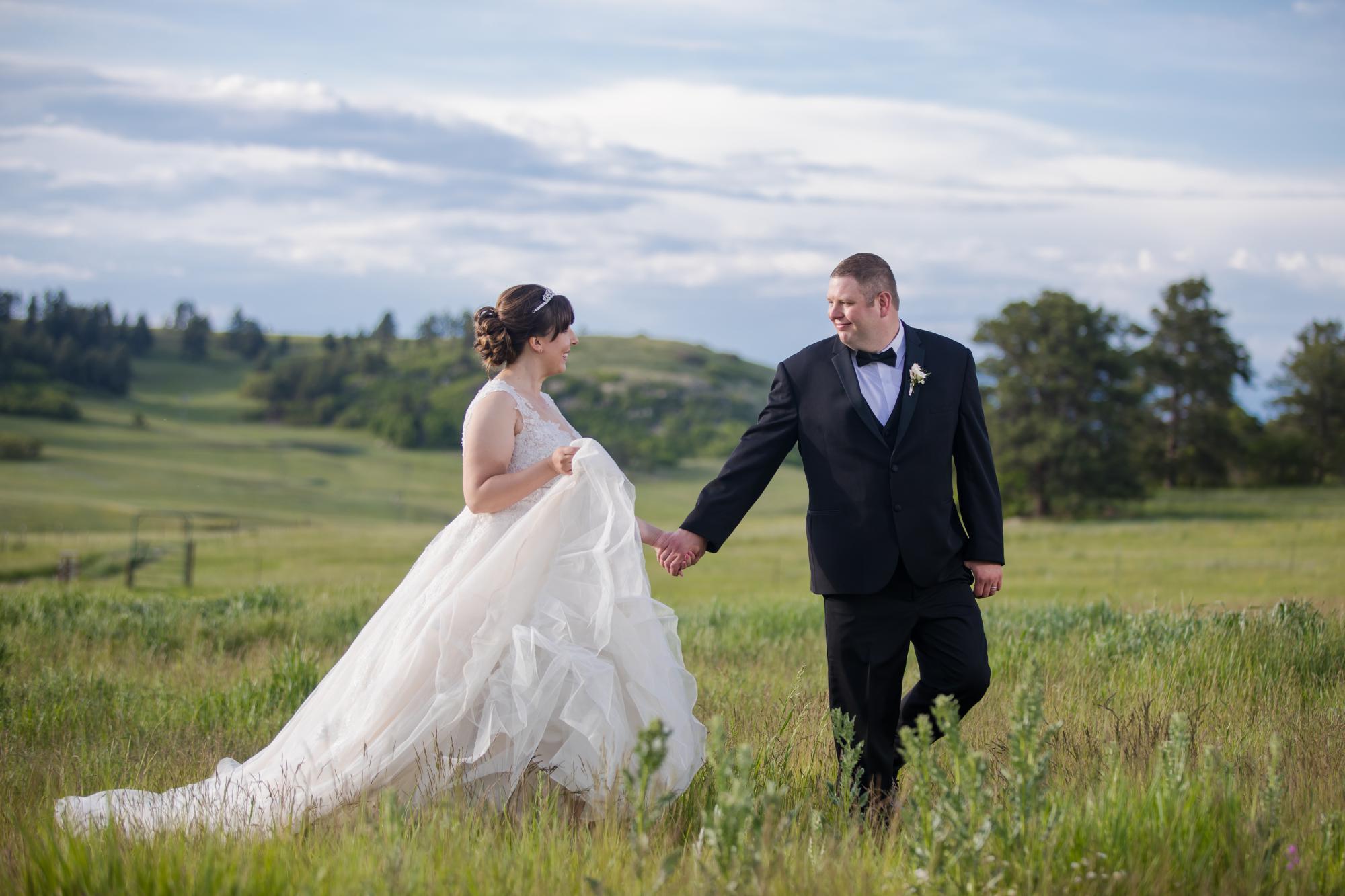 Newly married couple walk through Colorado Springs field