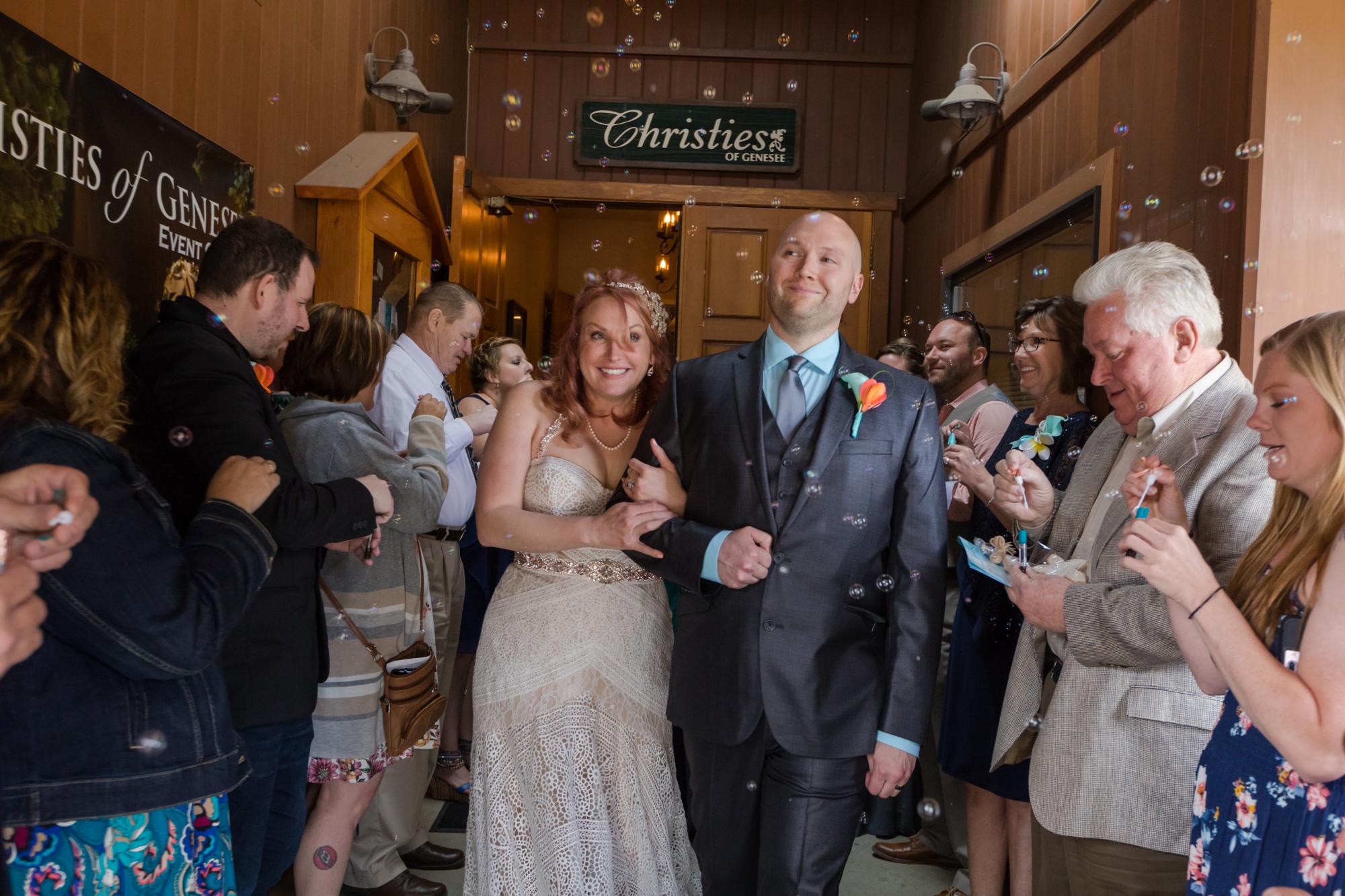 newlyweds walk past family and friends with bubbles
