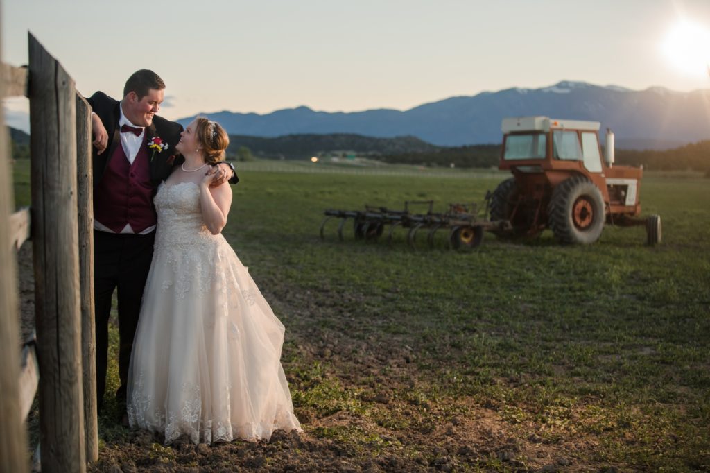 bride and groom pose with tractor