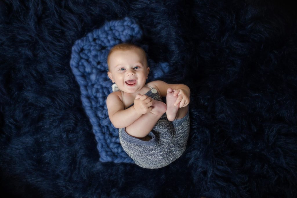 Baby holds feet in milestone photography session