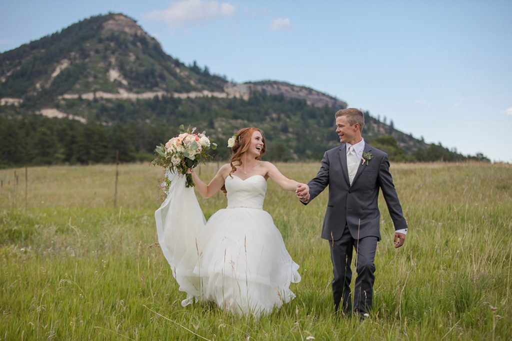 bride and groom running in meadow