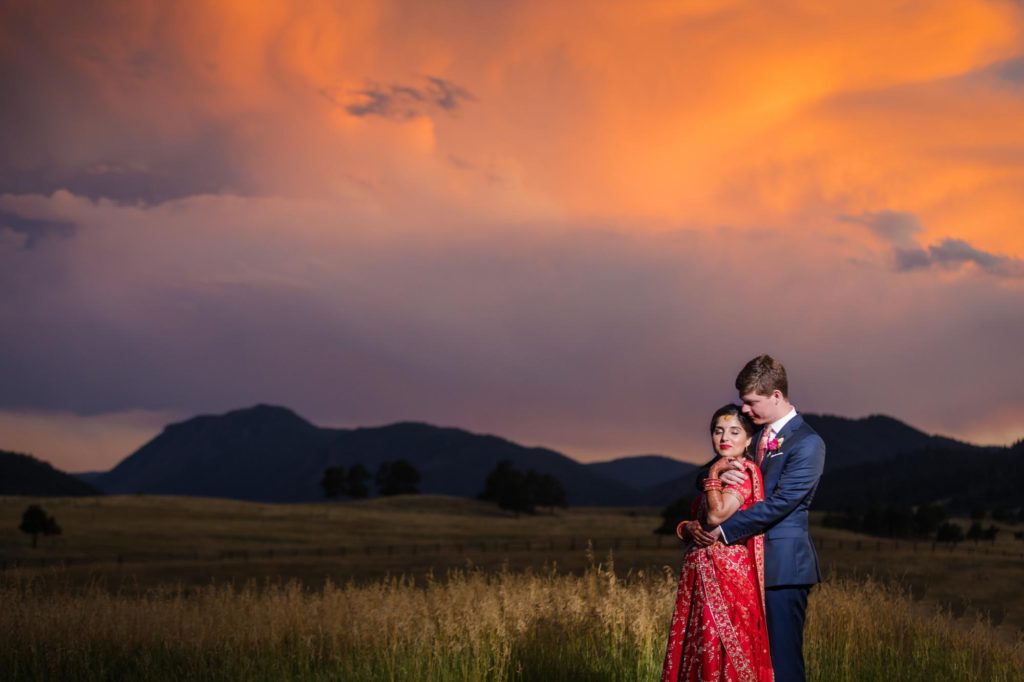 Traditional Indian wedding couple pose in front of stunning sunset