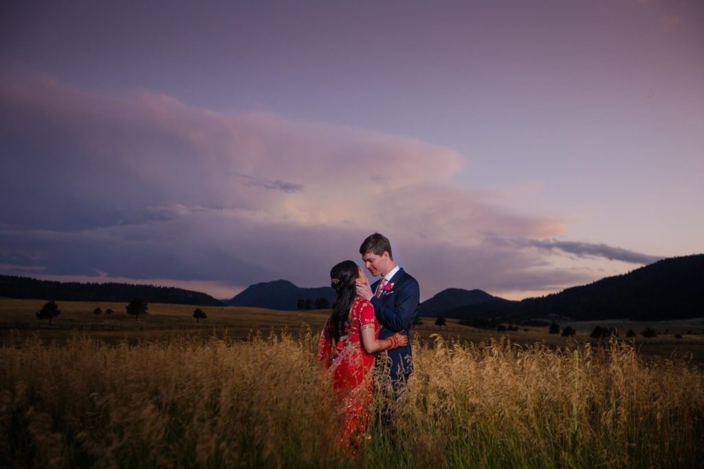 bride and groom gaze out at rocky mountains during sunset