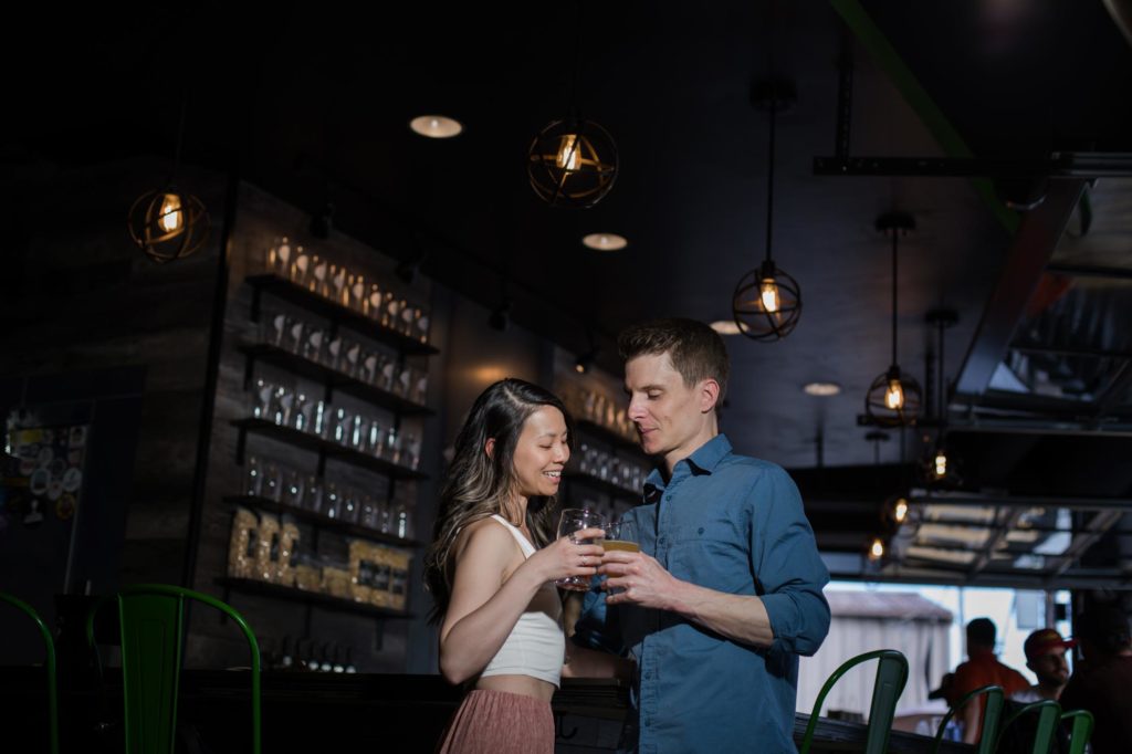 engaged couple toasts beer in rino denver