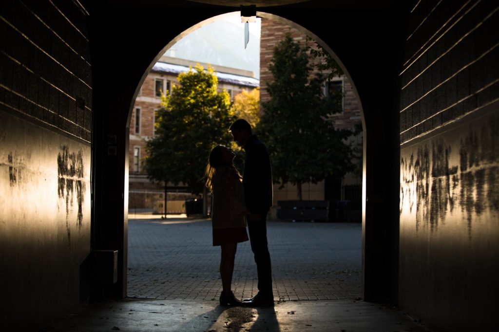 Boulder engaged couple kisses under arch