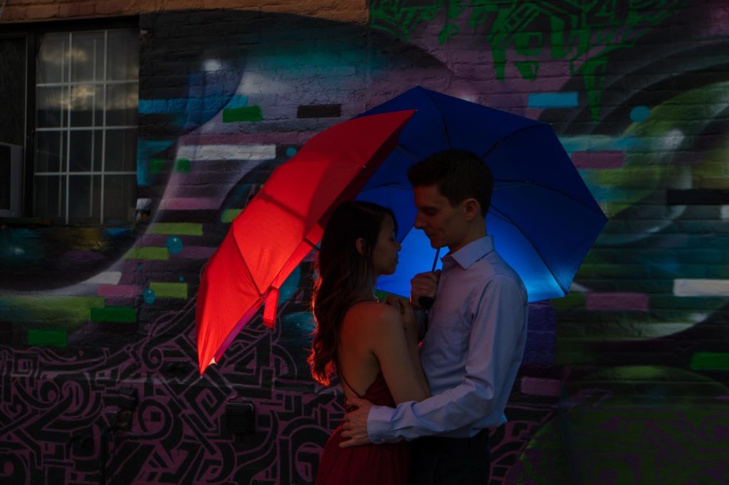 Couple poses under red and blue umbrella