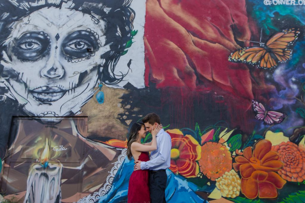 couple poses in front of dia de los muertos mural in rino engagement session