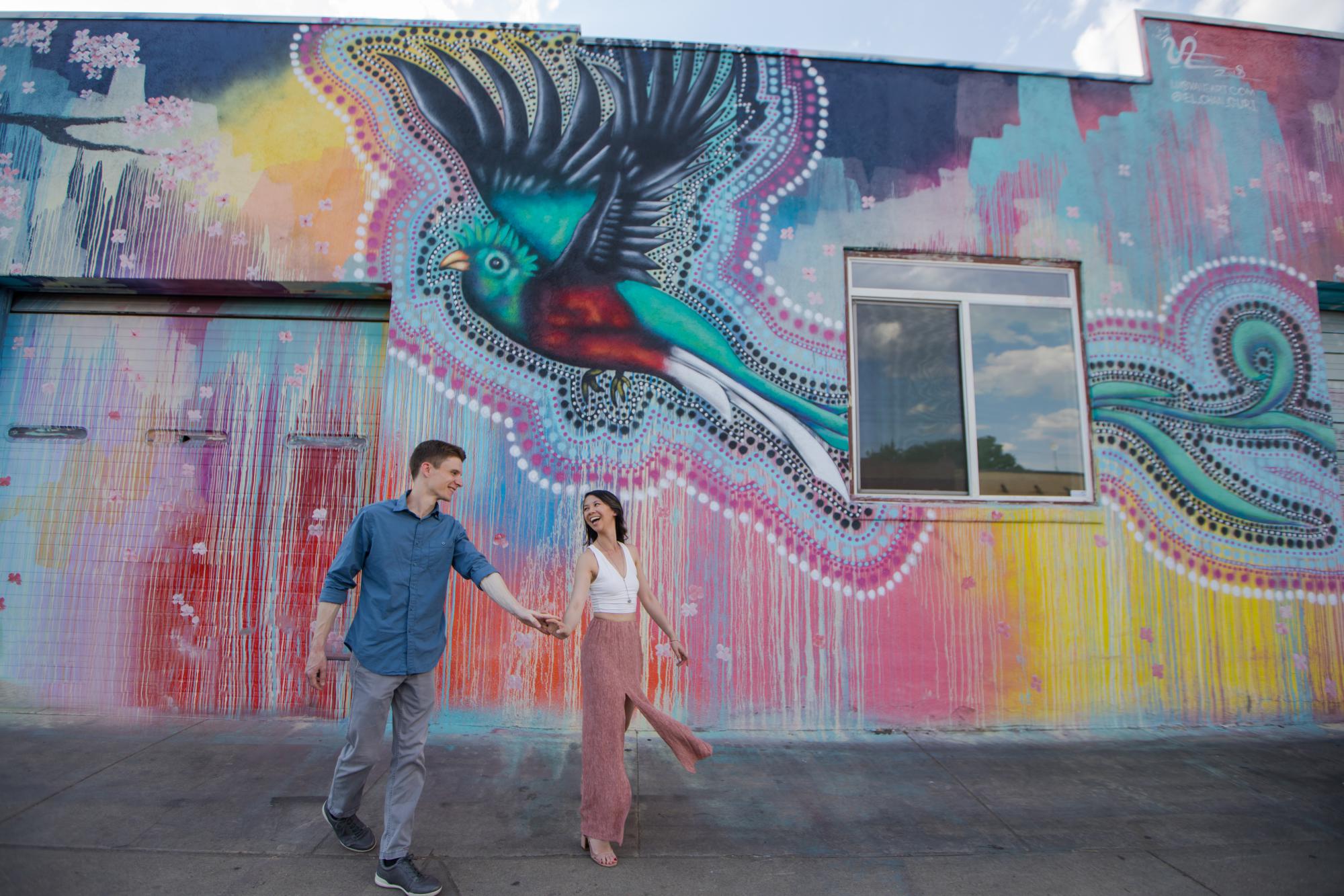 couple run in front of El Chan Guri mural in RiNo Denver