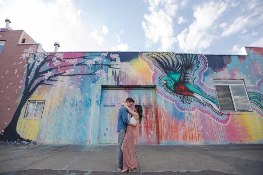 couple kisses in front of murals in artsy engagement portraits