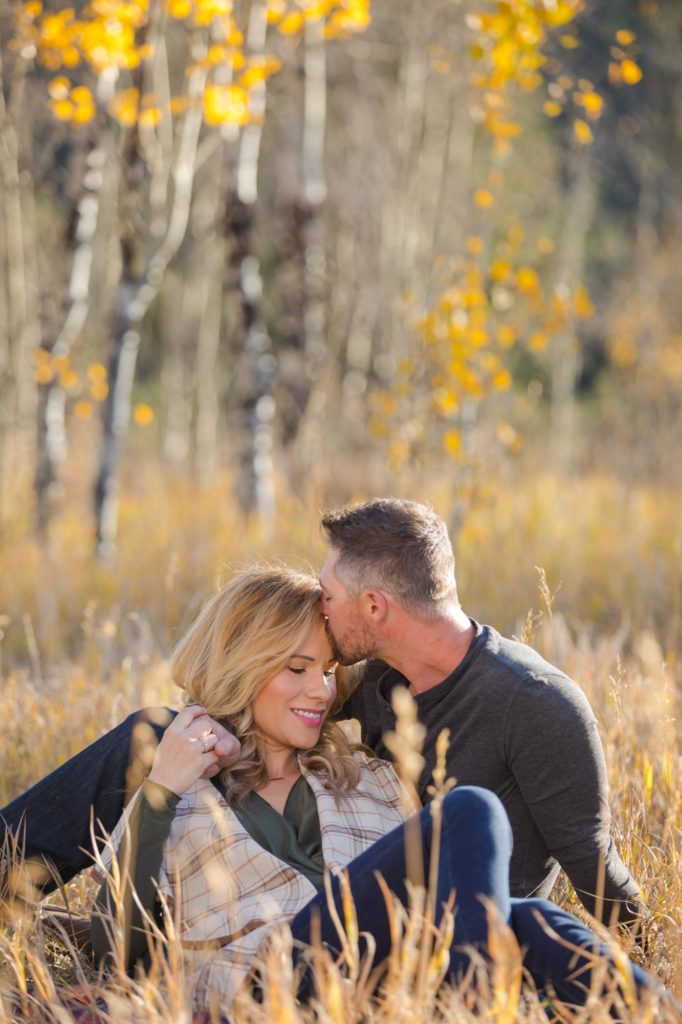 engaged couple kiss in a field
