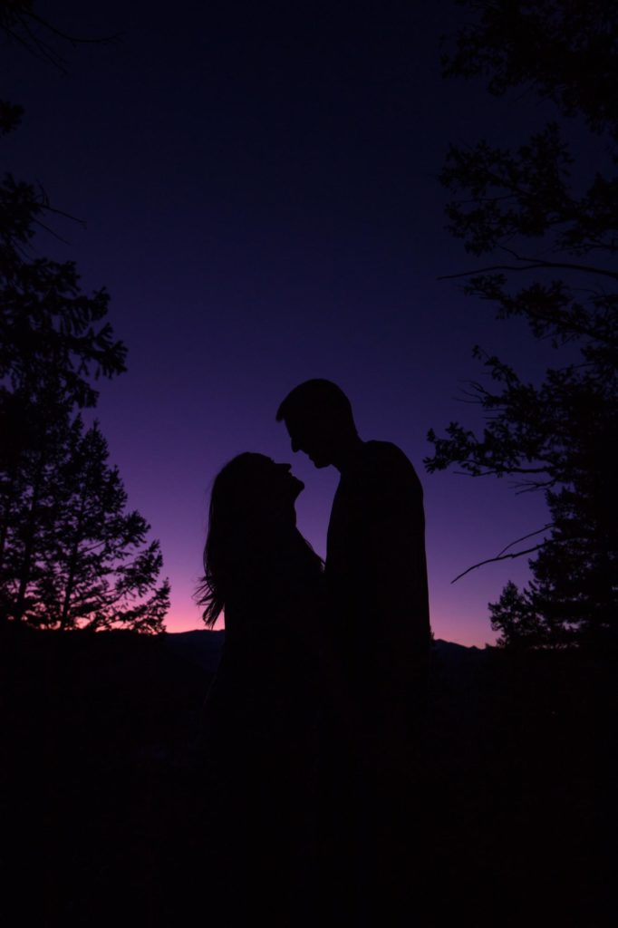 engaged couple silhouetted against sunset