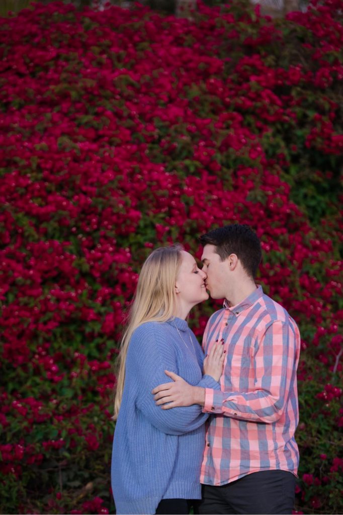 couple kisses in front of flower wall in Santa Barbara