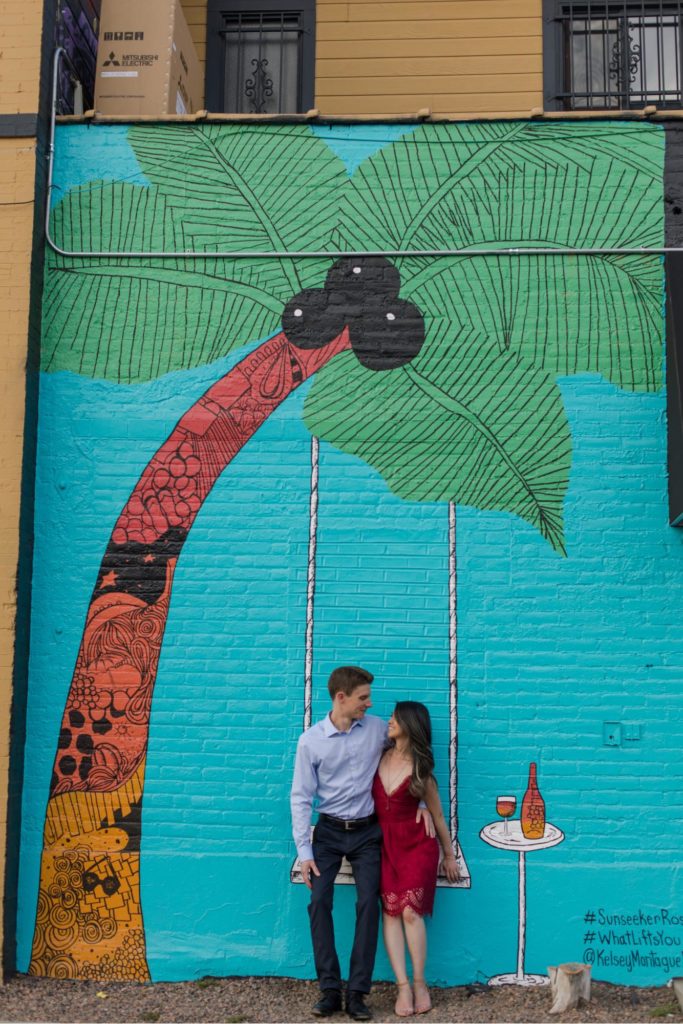 DEnver engaged couple poses in front of tropical mural